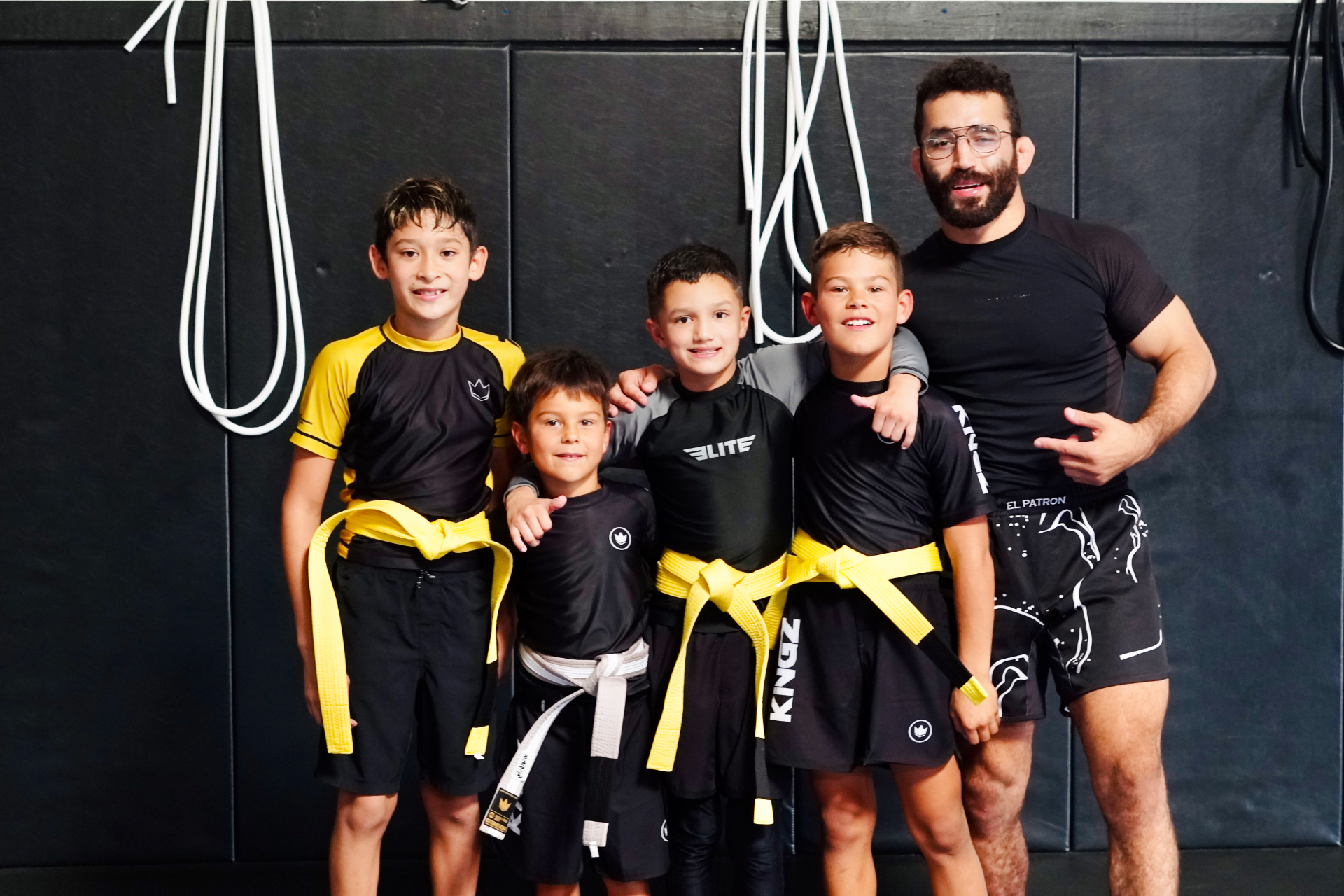 Young GDA jiu-jitsu athletes in yellow and white belts with their coach in San Diego